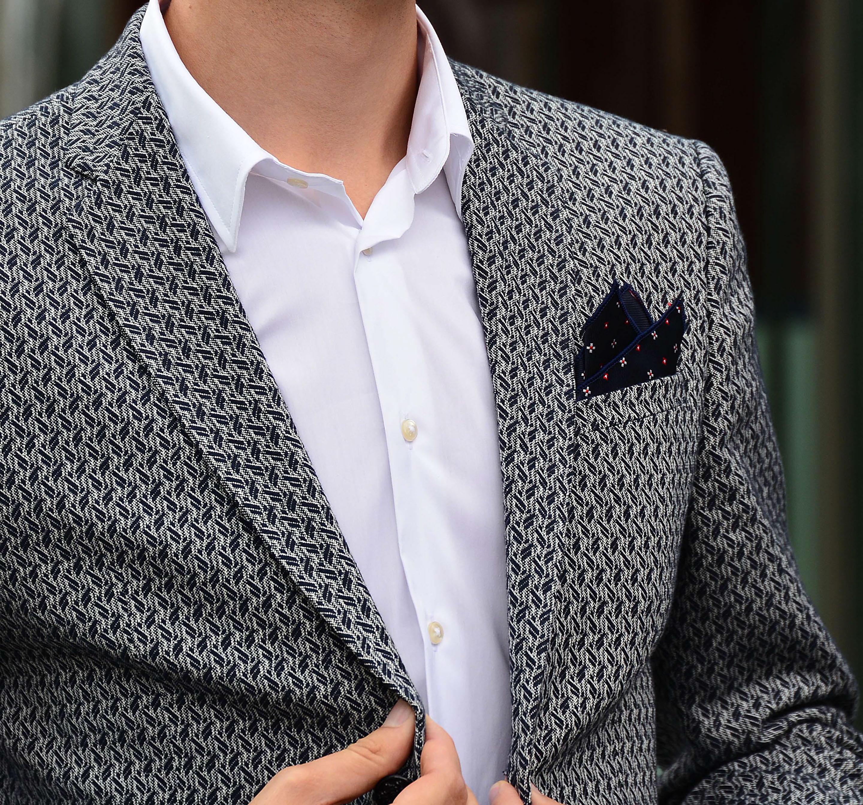 Four self-confident men wearing di Venisco pocket squares standing in front of a modern building.