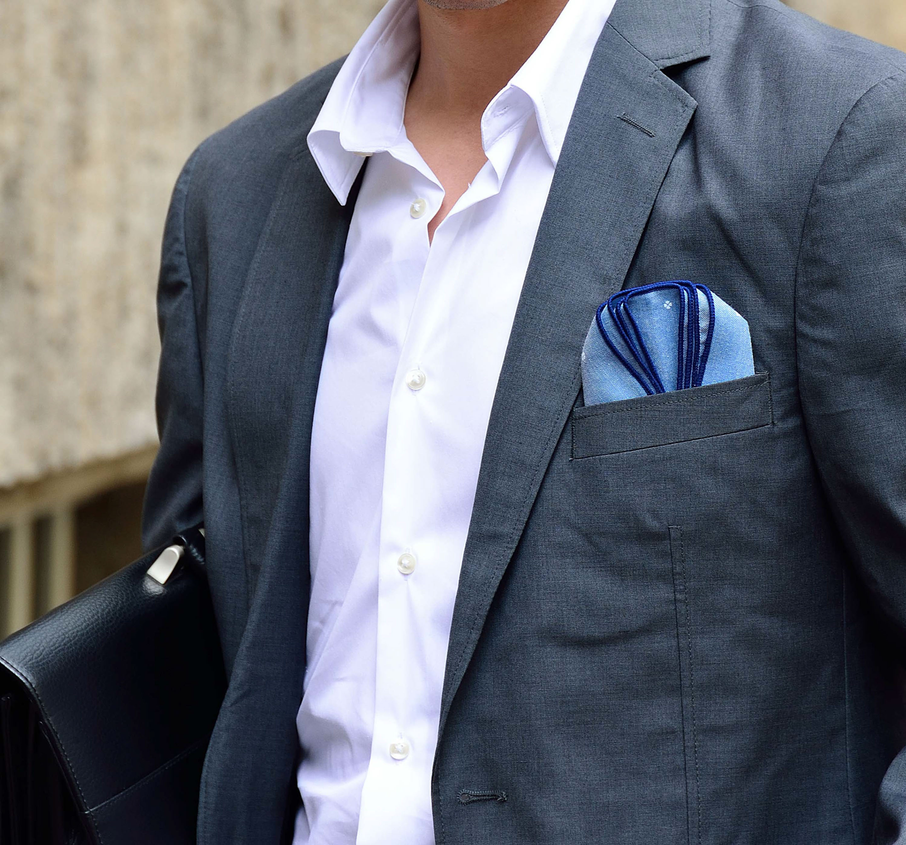 Four self-confident men wearing di Venisco pocket squares standing in front of a modern building.