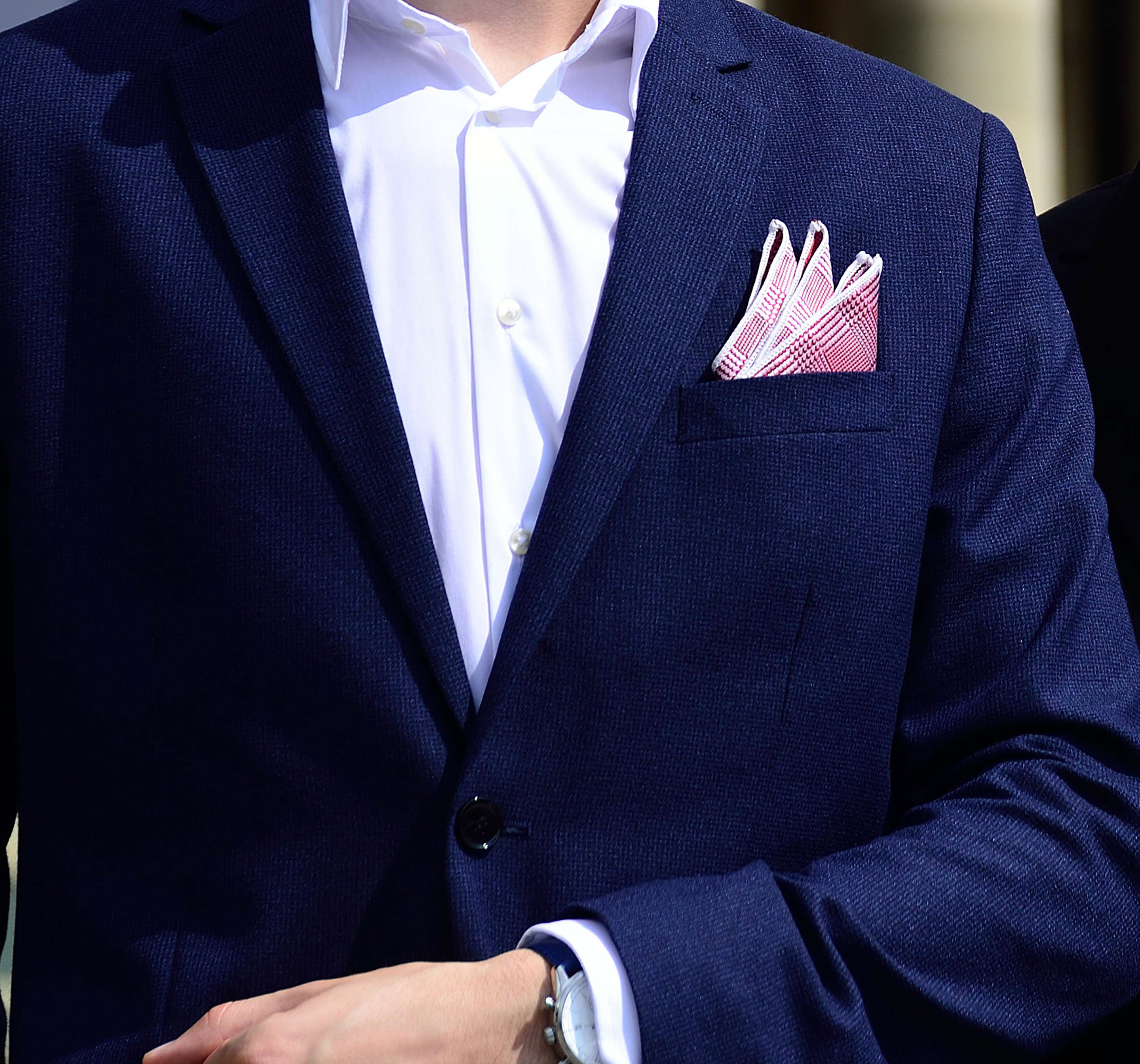 Four self-confident men wearing di Venisco pocket squares standing in front of a modern building.