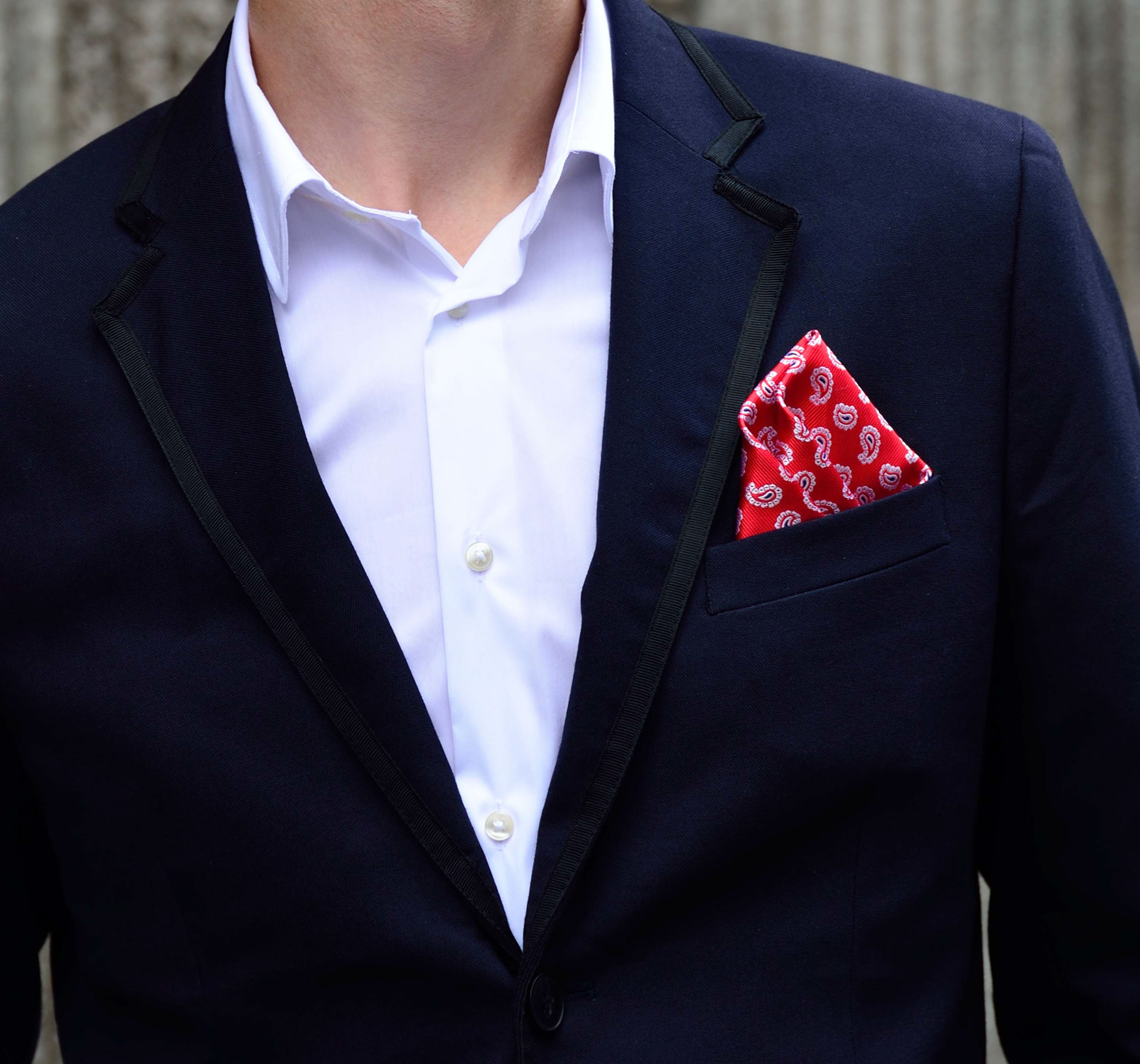 Four self-confident men wearing di Venisco pocket squares standing in front of a modern building.